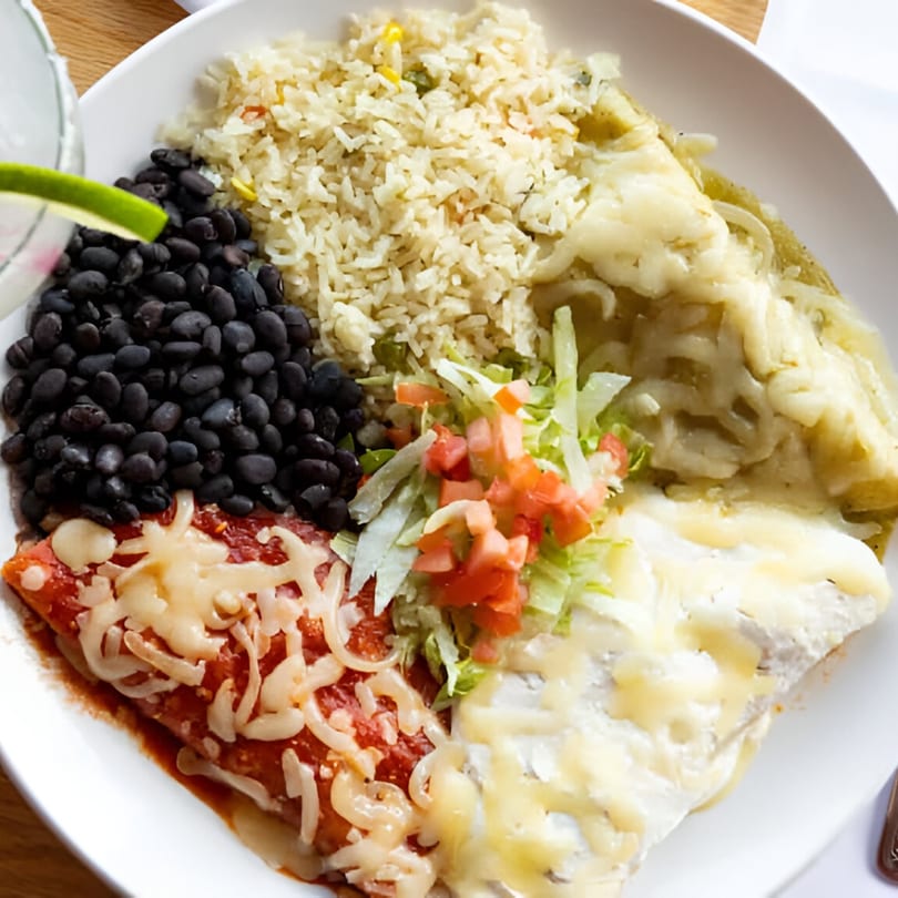 A Blue Agave Mexican combo plate with enchiladas, rice, black beans, and a lime wedge.