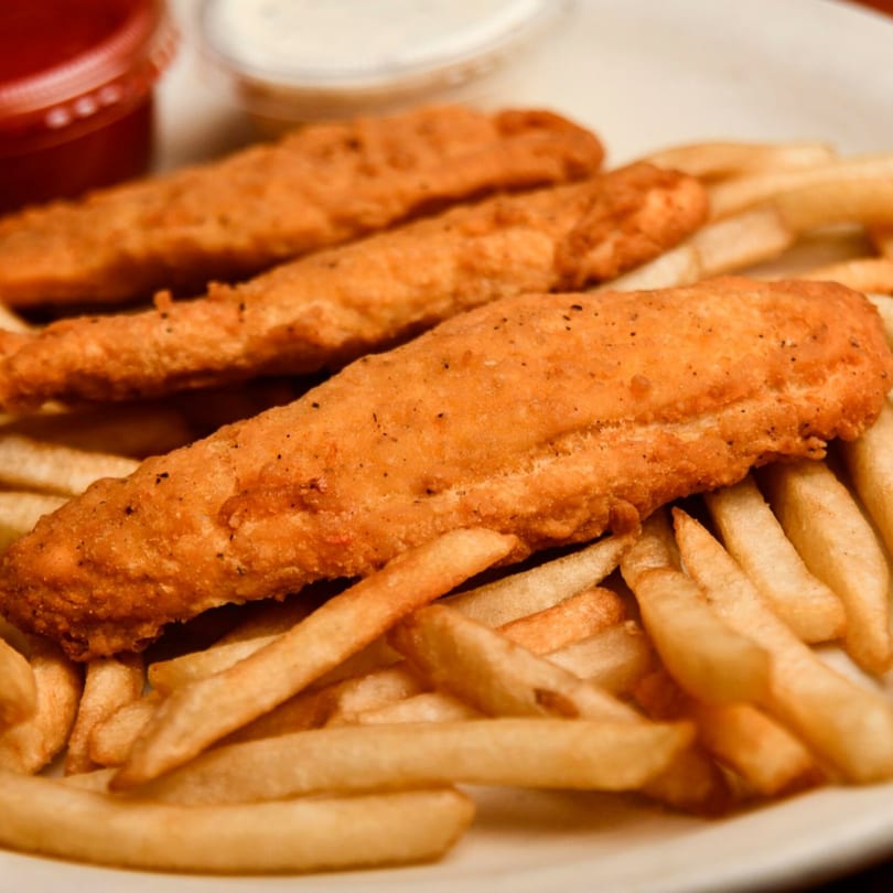 Three crispy fried fish fillets and a pile of golden french fries with dipping sauces.